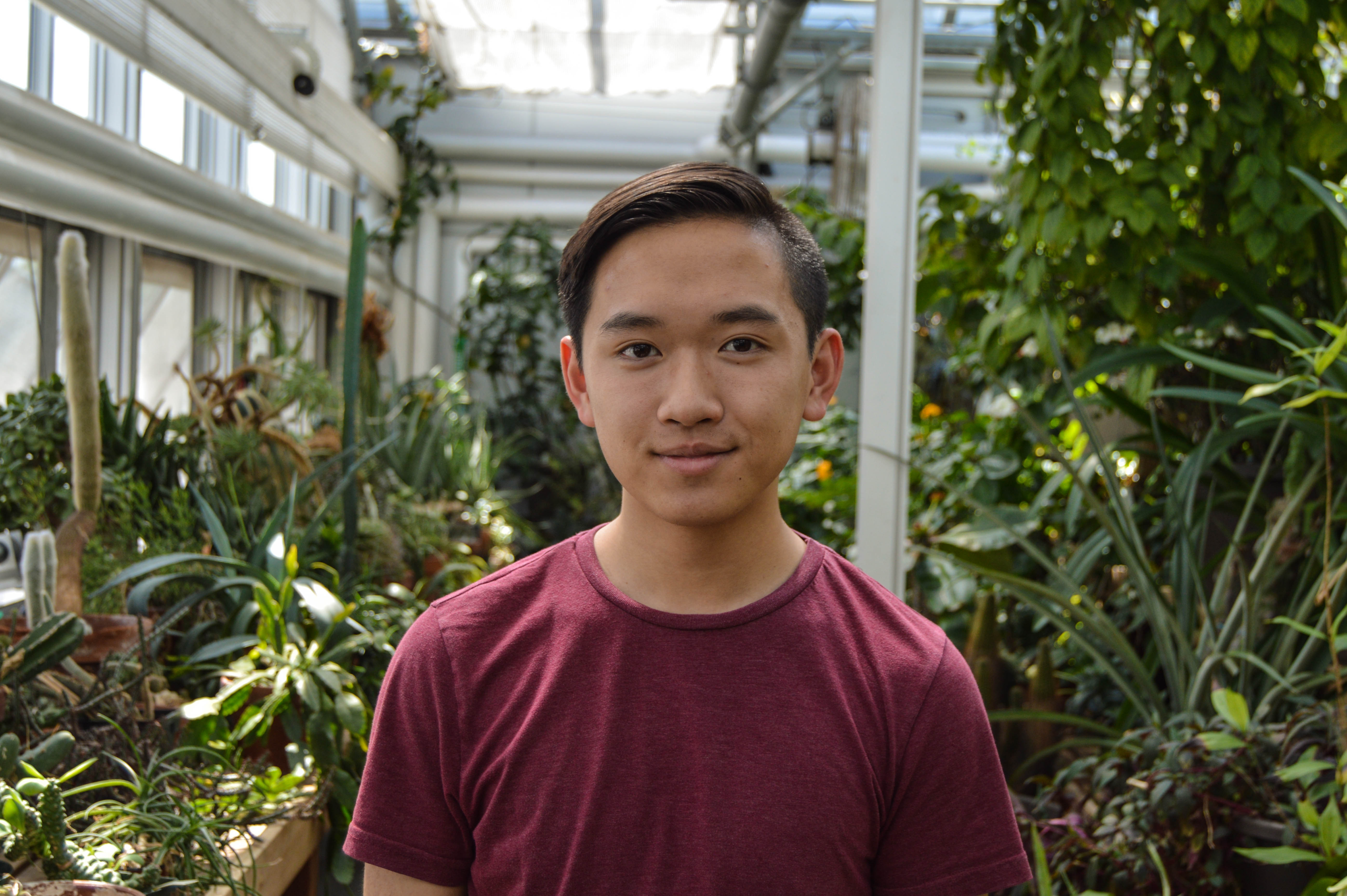 Photo of man in red shirt in front of plants